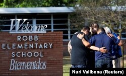 Profesorii de la Școala primară Robb din Uvalde/Texas se îmbrățișează după ce un atac armat a avut loc în școala unde predau.