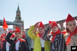 Дівчатка у червоних пілотках та галстуках на шиї салютують під час церемонії вступу до організації піонерів та 100-річчя Всесоюзної піонерської організації в Москві. Росія, 22 травня 2022 року