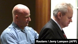 Колишнього президента Югославії Слободана Мілошевича (праворуч) ведуть до зали суду Трибуналу ООН