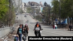 Mariupol residents travel along a road in the port city in April.