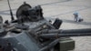 Un copil se uită la turela unui tanc rusesc distrus, în timpul unei expoziții în centrul Kievului care prezintă vehicule militare rusești distruse, Ucraina, 21 mai 2022