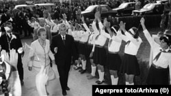 Pionieri în uniformă îi întâmpină pe dictatorul Nicolae Ceaușescu și pe soția sa, Elena.