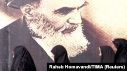 Iranian women walk past a poster of the late Supreme Leader Ayatollah Ruhollah Khomeini, who died in 1989. (file photo)