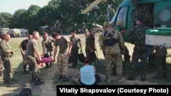 Поранені, зокрема цивільна жінка, готуються летіти з польового шпиталю до стаціонарних медичних закладів. Літо 2014 року