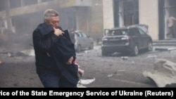 Олександр Волобуєв виносить дитину на руках з дитячого садка у Харкові, куди влучили російські безпілотники. 22 жовтня 2025 року