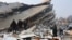 People look at rubble and damage following an earthquake in Hatay, Turkey
