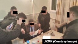 Мамлекеттик кызматкерлердин бири кармоо учурунда тартылган сүрөт.