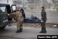 Militarii ucraineni ridică cadavrul unui bărbat care a fost împușcat când un vehicul blindat rus a trecut pe lângă acesta, în nordul Kievului, pe 25 februarie 2022.