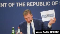 Presidenti i Serbisë, Aleksandar Vuçiq, duke mbajtur në duar një letër me targa KS. Këto targa, Serbia ka propozuar që të përdoren nga serbët në Kosovë. Por, Qeveria e Kosovës ka thënë se nuk mund të pranojë targa që kanë status neutral ndaj shtetësisë së Kosovës. 
