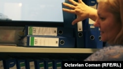 Angajat al CNSAS prezintă bibliorafturile cu solicitări de documente.