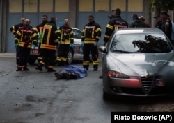 Firefighters stand next to the body of one of the victims of the August 12 attack in Cetinje.