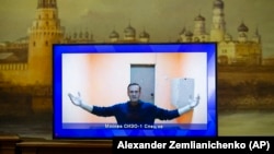 Defunctul lider al opoziției ruse, Alexei Navalnîi, pe un ecran de televiziune în timpul audierii sale la o instanță din Moscova, în ianuarie 2021.