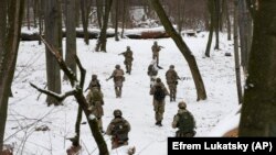 Membri ai Forțelor Teritoriale de Apărare ale Ucrainei, unități militare voluntare ale Forțelor Armate, se antrenează într-un parc din Kiev, Ucraina. Fotografie realizată sâmbătă, 22 ianuarie 2022.