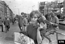 Прага, 1968 год, савецкая акупацыя і падаўленьне Праскай вясны. Людзі на вуліцах слухаюць радыё. Справа можна пабачыць каркас будынку будучага фэдэральнага парлямэнту Чэхаславаччыны, у якім у 1995 годзе разьмесьціцца Радыё Свабода