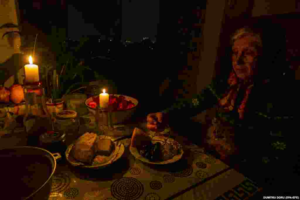 O femeie din Chișinău ia cina la lumina lumânărilor, ca parte a măsurilor de economisire a energiei