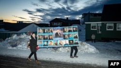 Men in the Greenlandic capital, Nuuk, carry a large poster for the Democrats party, which topped the polls in parliamentary elections on March 11. 
