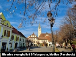 Imagine din centrul vechi al Mediașului, cu biserica evanghelică în plan depărtat. Aceasta este faimoasă și pentru turnul ei ușor înclinat.