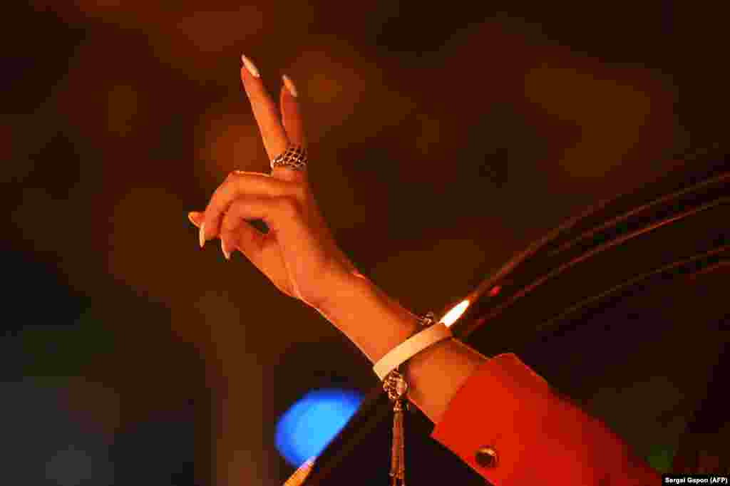 A woman wearing a white bracelet, a symbol of the opposition, gestures from a car during a rally on the night of August 11.