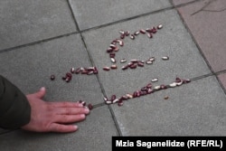 "ლობიოს პროტესტი" საქალაქო სასამართლოსთან - ლაშა ჩხარტიშვილის მხარდამჭერებმა მმართველი პარტიის საარჩევნო ნომერი გამოსახეს ლობიოს მარცვლებით