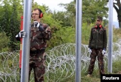 Militari unguri înălțînd un gard împotriva refugiaților la granița cu Croația