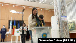 A mother holds her child over a ballot box at a polling station in Moldova's parliamentary elections on September 28.
