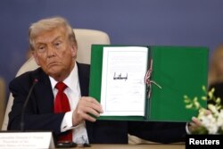Președintele SUA, Donald Trump, pozează cu acordul semnat la summitul liderilor mondiali privind încheierea războiului din Gaza, între Israel și Hamas. Sharm el-Sheikh, Egipt, 13 octombrie 2025.