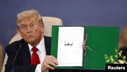 Американскиот претседател Доналд Трамп со потпишаниот договор на самитот на светските лидери за завршување на војната во Газа, во Шарм ел Шеик, Египет, на 13 октомври 2025 година.