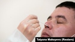 RUSSIA -- A health worker wearing protective gear takes a swab from a man to test for the coronavirus disease (COVID-19) at clinic in Moscow, Russia October 1, 2020. 