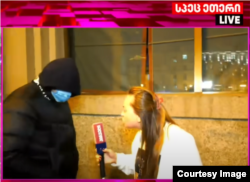 ასე გამოიყურებოდა პოლიციელი მირიან ქავთარაძე 2024 წლის დეკემბერს - ეფარა ქუდი, ეკეტა პირბადე. ფოტო ამოჭრილია ტელეკომპანია „პირველის“ პირდაპირი ეთერიდან. ეს ამბავი ტელევიზიამ გააშუქა სათაურით - „ოლიგარქის ომონის სახე - ვინ არიან და როგორ იქცევიან პირბადიანი ჩასაფრებული ტიტუშკები“