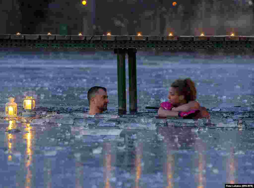 Два члени групи Cold Water Tribe (&laquo;Плем'я холодної води&raquo;) розмовляють, купаючись у крижаній воді замерзлого озера в Верешегіхазе, Угорщина