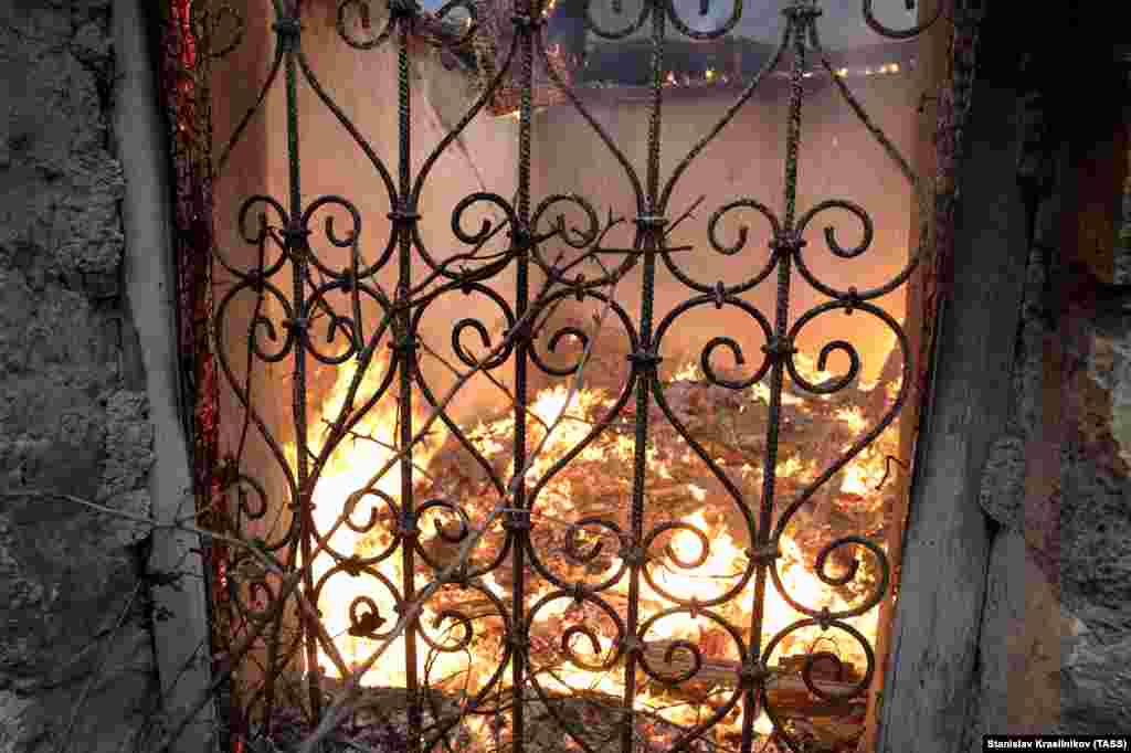 A home smolders in Charektar/Caraktar village.