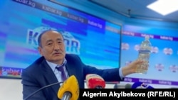 Саламаттыкты сактоо жана социалдык өнүктүрүү министри Алымкадыр Бейшеналиев басма сөз жыйынында уу коргошунду көрсөтүп жатат 