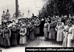 Урочистості з нагоди проголошення Української Народної Республіки на Софійській площі. Київ, 7(20) листопада 1917 року. Ліворуч: група військових. У центрі (зліва направо): генеральний секретар військових справ Симон Петлюра, голова Генерального секретаріату Володимир Винниченко, голова Центральної Ради Михайло Грушевський. Праворуч: військові та група військових аташе країн Антанти