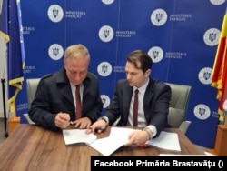 Primarul din Brastavățu, Constantin Oprea (stânga), și Sebastian Burduja, ministru al Energiei la acea vreme, la semnarea unui contract de eficientizare a consumului de energie electrică în comună - martie 2025.