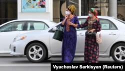 Ýüzi maskaly ýolagçylar köçeden geçýärler (arhiw suraty)