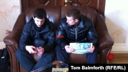 Pro-Maidan security guards sit on a black sofa blocking Kharkiv Governor Mykhaylo Dobkin's office in the regional administration building.