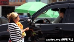 Баласын көтеріп, жол бойында қайыр сұрап жүрген әйел. Азаттық архивіндегі фото.