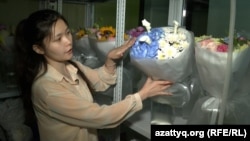 Алматыдағы гүл сататын дүкеннің қызметкері Жансая Қытайдан әкелінген гүлдерді көрсетіп тұр. 2025 жылдың шілде айы.