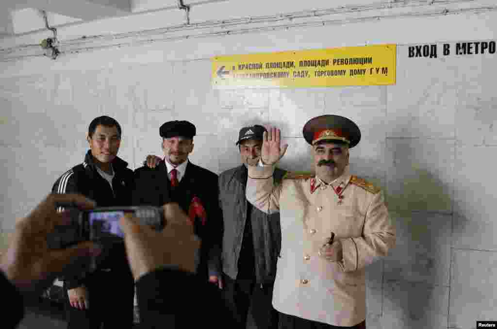 Трудовые мигранты фотографируются с двойниками Ленина и Сталина в Москве. 2011.