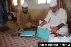 Mian Mohammad Javed (right) and his son, Mian Noor Muhammad, with their records of conversion at the Bharchundi Dargah seminary. Javed says he has converted over 100 people to Islam since 2015.