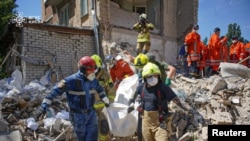 Рятувальники несуть тіло людини, знайдене під завалами житлового будинку, який постраждав від російського ракетного удару, Київ, 9 липня 2024 року.