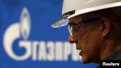 Un muncitor care lucrează pentru Gazprom surpins lângă logo-ul companiei
