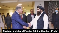 شاه محمود قریشی وزیر خارجه پاکستان (چپ) حین مصافحه با سرپرست وزارت خارجه حکومت طالبان در اسلام آباد. ۱۸ دسمبر ۲۰۲۱
