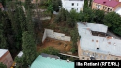 ახალი მშენებლობის ადგილი ბარნოვის ქუჩის პირველ ჩიხში. საცხოვრებელ სახლს, ფოტოზე მარჯვნივ, 2007 წლიდან არქიტექტურული ძეგლის სტატუსი აქვს და ავარიულია. ავარიულია მშენებლობის წინ მდგარი ცისფერსახურავიანი შენობა.. ფოტო: 19 სექტემბერი, 2025