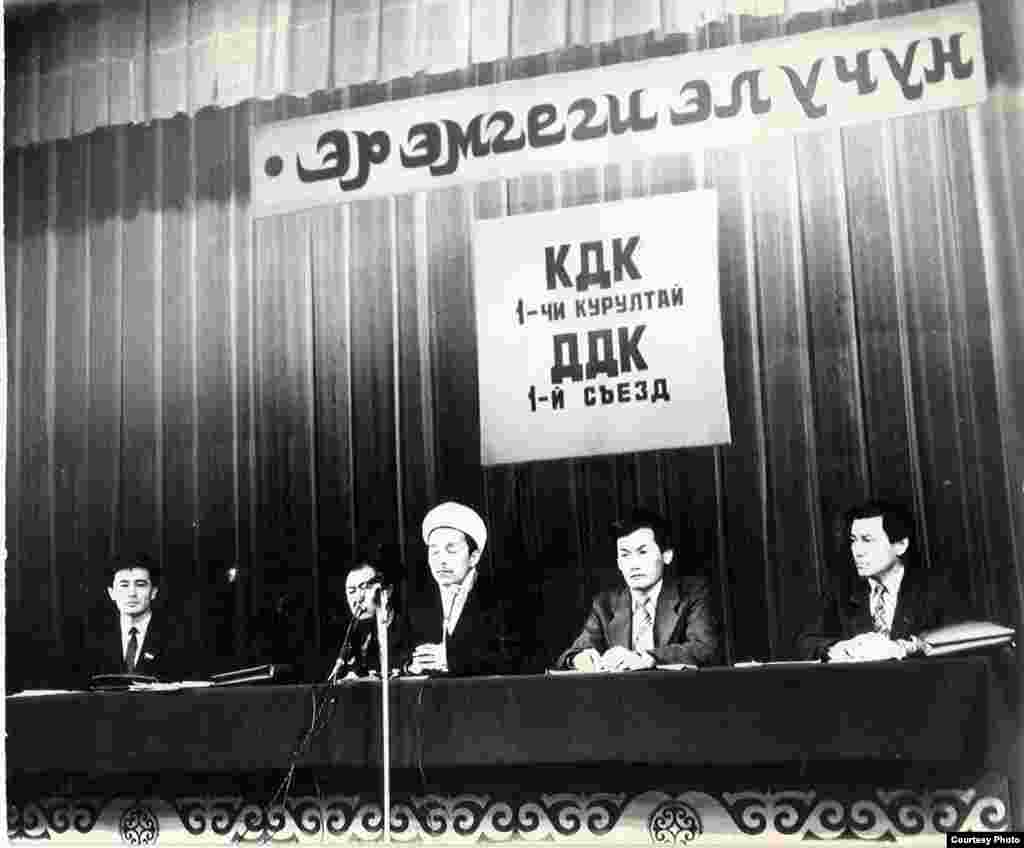 1991-жылдын 9-10-февралында өткөрүлгөн КДКнын Биринчи курултайынын ачылыш салтанаты маалында. Төрдө отургандар - Өмүрбек Текебаев, депутат жана КДКнын мүчөсү, Казат Акматов, депутат жана КДКнын теңтөрагасы, Дүйшөнбек Отонбай уулу, Кыргызстандын муфтийинин катчысы, Кадыр Маматказиев, КДКнын теңтөрагасы жана Жыпар Жекшеев, КДКнын теңтөрагасы (солдон оңго).&nbsp;