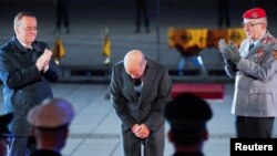 Cancelarul german în funcție, Olaf Scholz (centru), se închină la o ceremonie militară (Grosser Zapfenstreich) pe 5 mai, luându-și rămas bun la final de mandat, find aplaudat de ministrul Apărării, Boris Pistorius (stânga) și inspectorul general al armatei, Carsten Breuer.