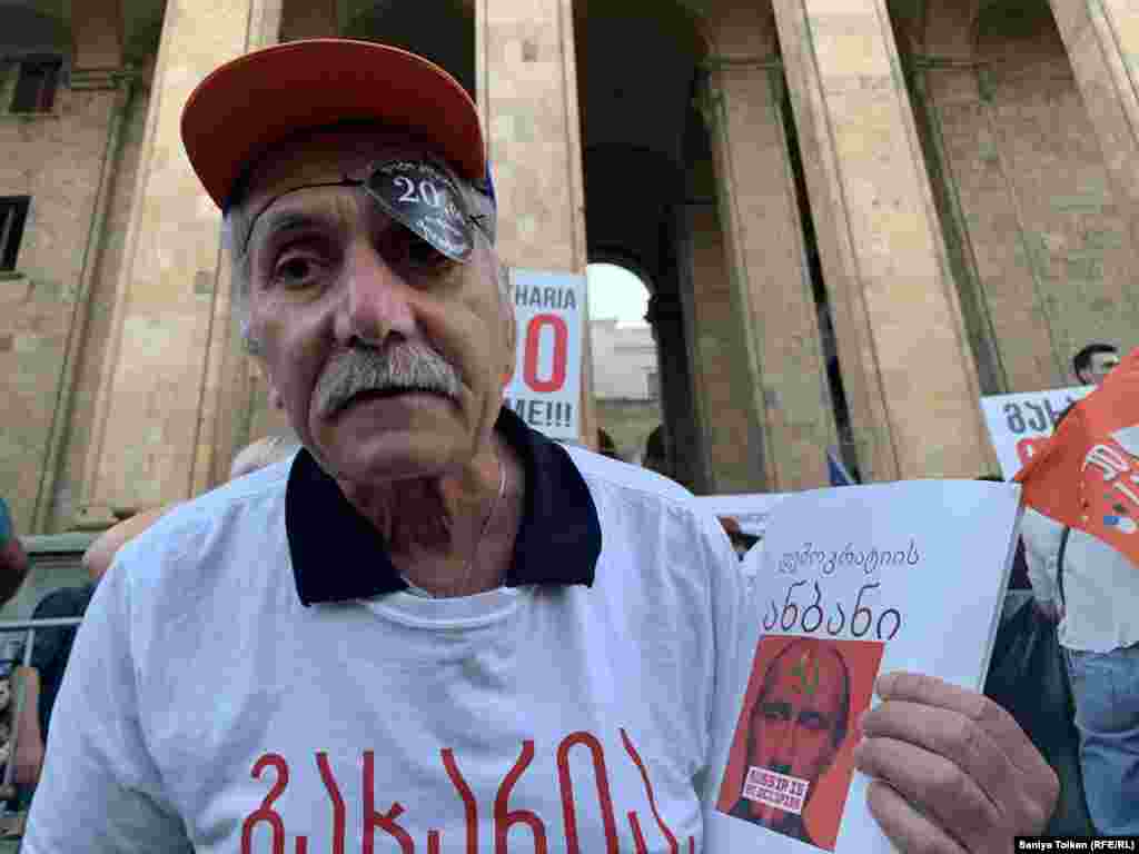 Қолына грузин тілінде "Демократия әліппесі. Ресей - басқыншы" деген жазу бар кітапша ұстап тұрған наразы азамат. Тбилиси, 3 шілде 2019 жыл.