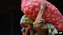 <p>Каптагы картөшкөнү көтөрүп бараткан жумушчу. Исламабад, Пакистан. 