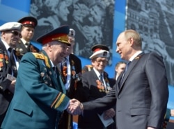 Russian President Vladimir Putin (right) shakes hands with a World War II veteran during Victory Day celebrations on Red Square in Moscow on May 9, 2015.