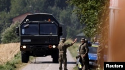 Солдаты стоят на страже возле места, где, как полагают, упал российский беспилотник после вторжения в воздушное пространство Польши 